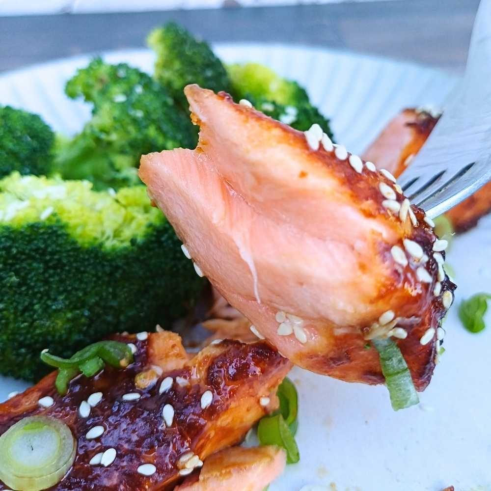 flakey piece of baked salmon on a fork showing inside