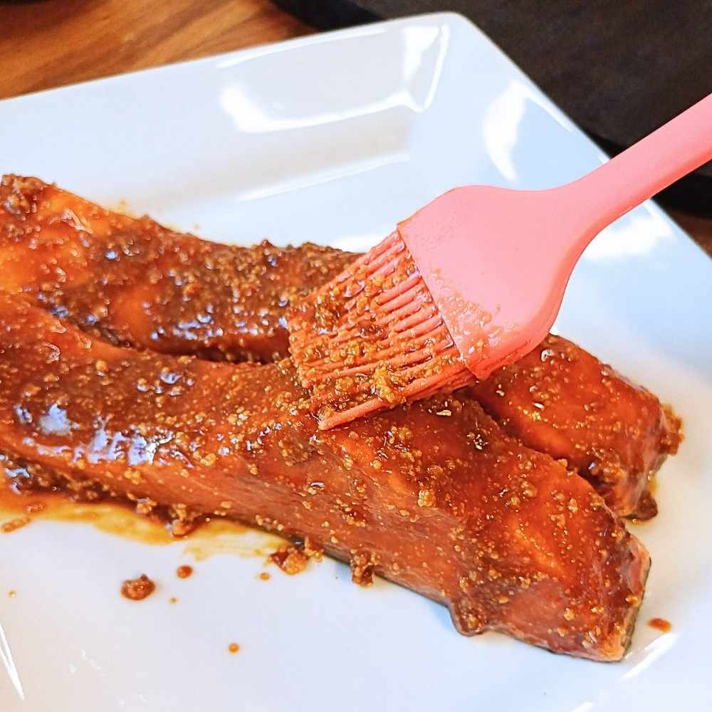 applying miso butter glaze to raw salmon fillets
