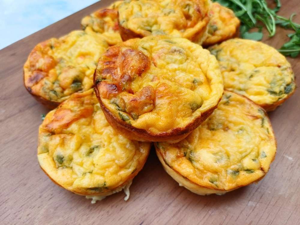 A few savory egg muffins made with vegetables inside on a wooden board