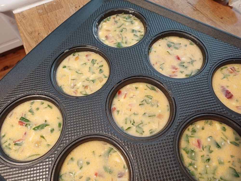 An uncooked cottage cheeese egg bites batter is in the muffin tray ready to be baked