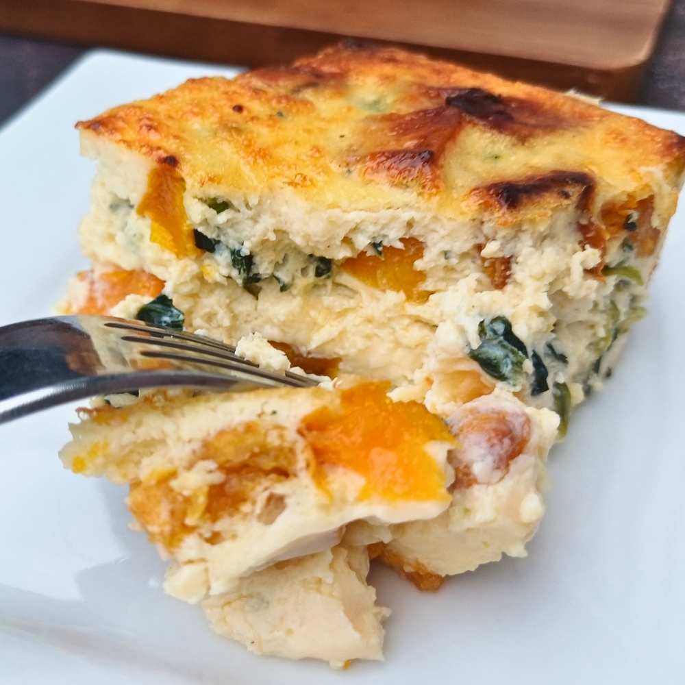 High protein egg bake with cottage cheese and roasted pumpkin and spinach, slice on a plate