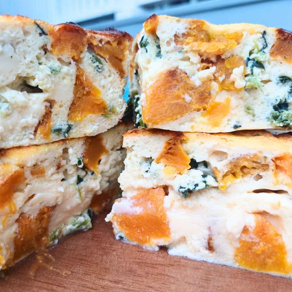 High protein cottage cheese and egg bake sliced on a board with vegetables