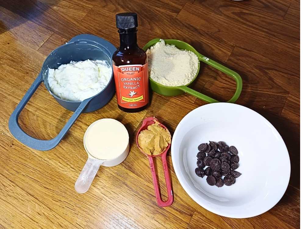 Simple ingredients for cottage cheese cookie dough, cottage cheese, almond flour, vanilla essence, peanut butter and chocolate chips.