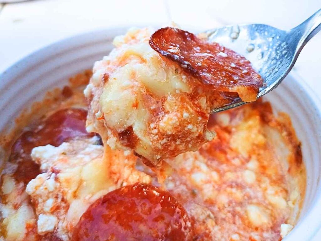 Close up of a cottage cheese pizza casserole on a spoon