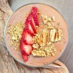 Top down view of a home made cottage cheese mousse dessert with strawberries and chopped walnuts.