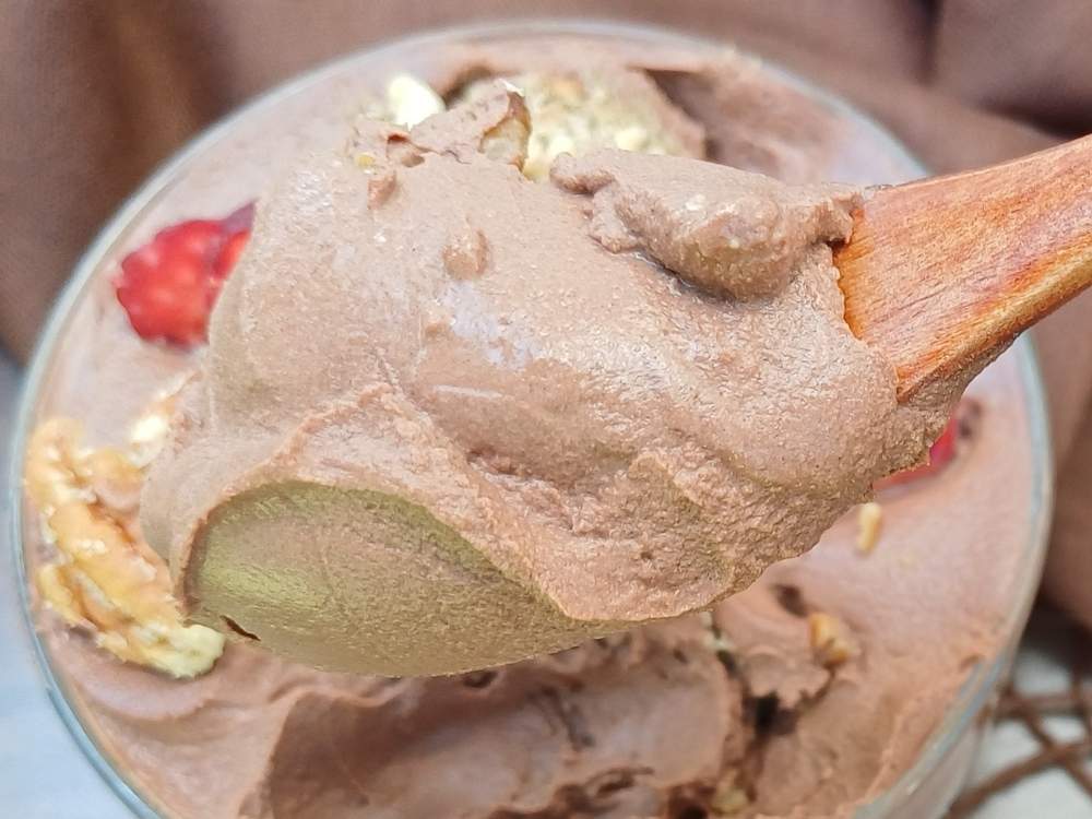 Close up of a creamy textrue of a chocolate mousse on a wooden spoon.