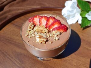 Cottage cheese chocolate mousse in a glass serving cup with white flowers in the background.