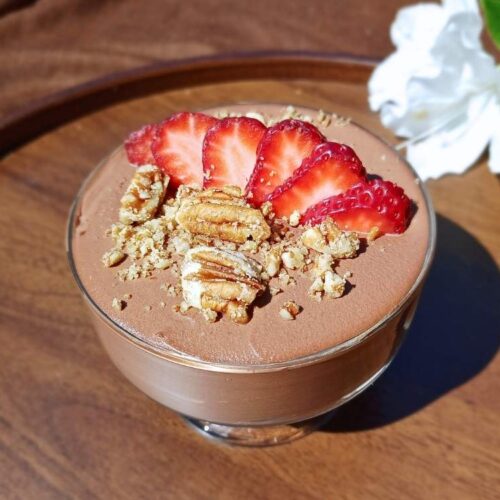 Cottage cheese chocolate mousse in a glass serving cup with white flowers in the background.