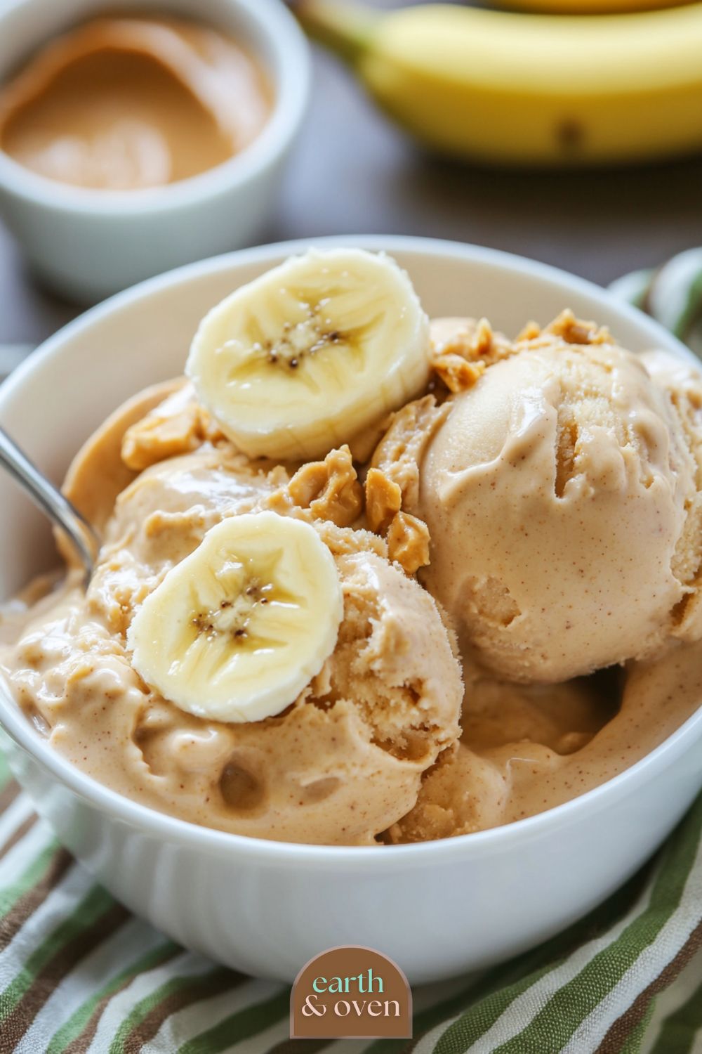 Banana Peanut protein Ninja creami ice cream scoops in a white bowl with slices of banana on top