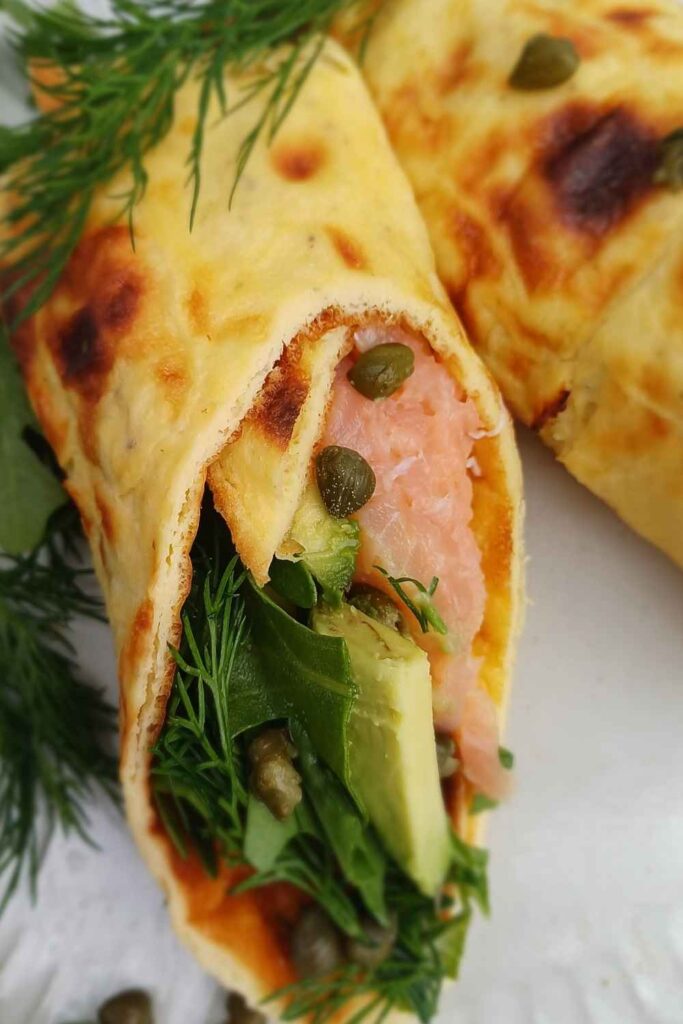 Smoked salmon and green salad with avocado wrapped in cottage cheese flatbread on a plate