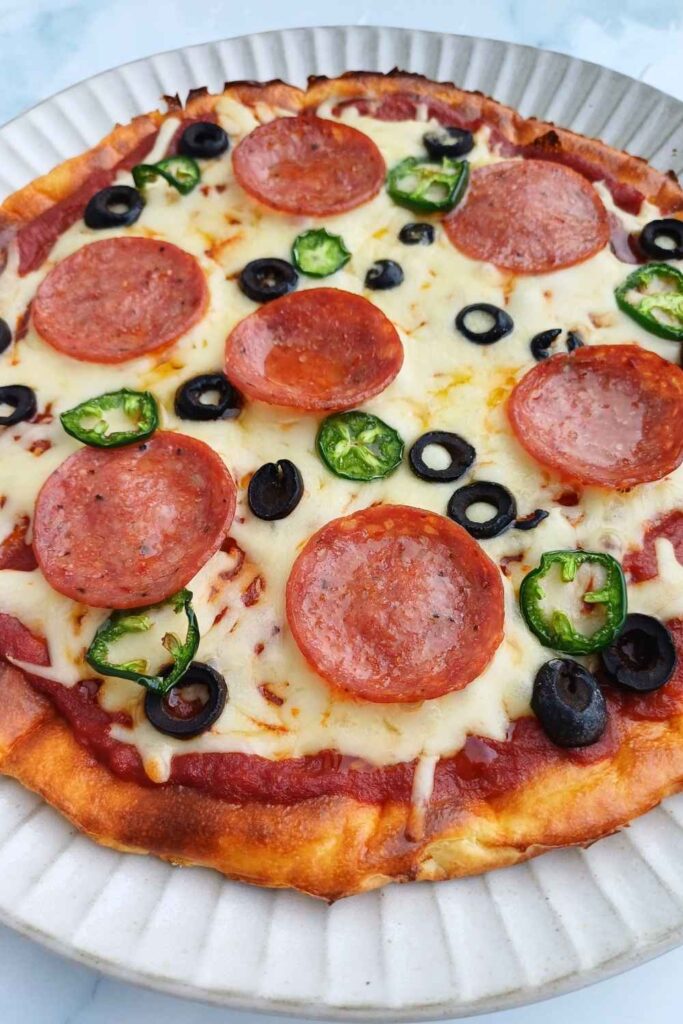 Pizza ingredients laid out on a low carb cottage cheese flatbread