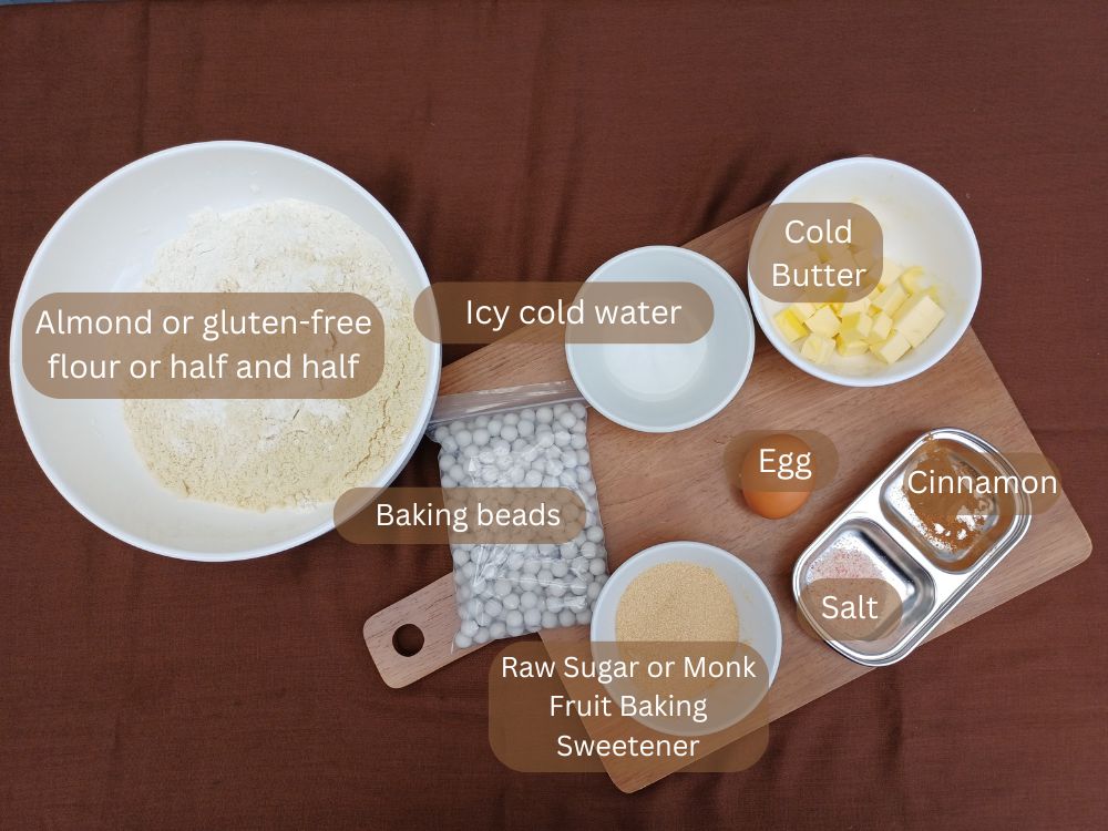 Ingredients for the gluten free pie crust including almond flour, sugar, eggs and baking beads layed out on the board