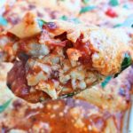 Juicy keto chicken parmesan casserole spooned out from a baking tray showing inside layers.