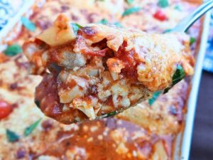 Juicy keto chicken parmesan casserole spooned out from a baking tray showing inside layers.