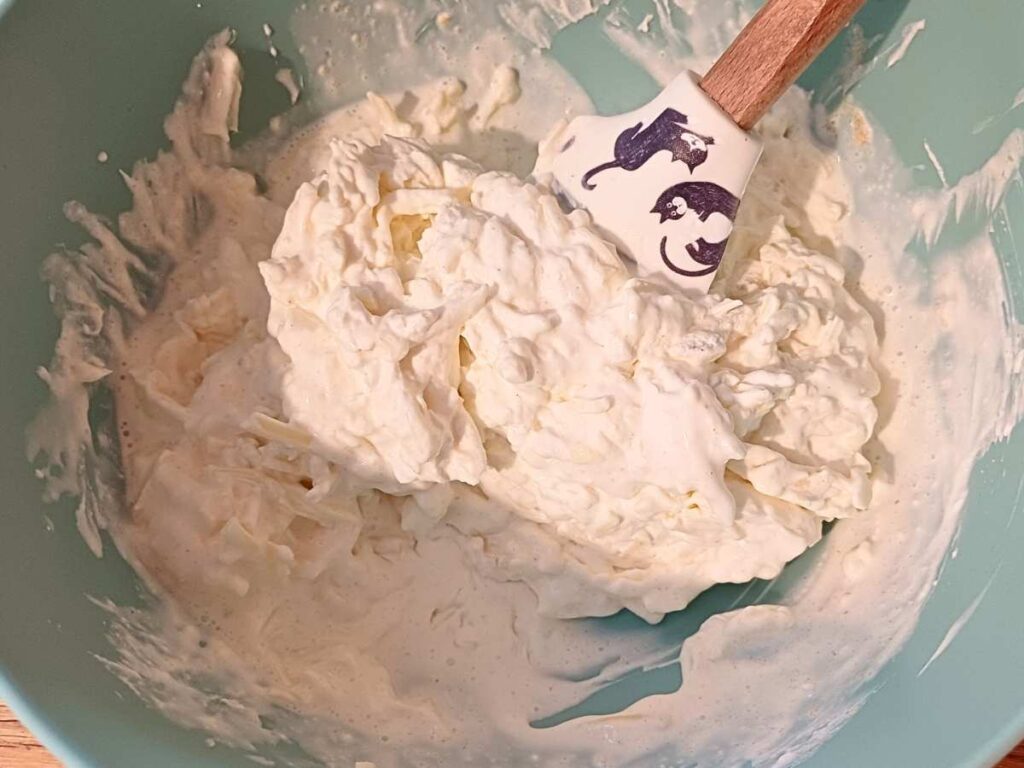 Creamy cheesy sauce in a bowl mixed with spatula