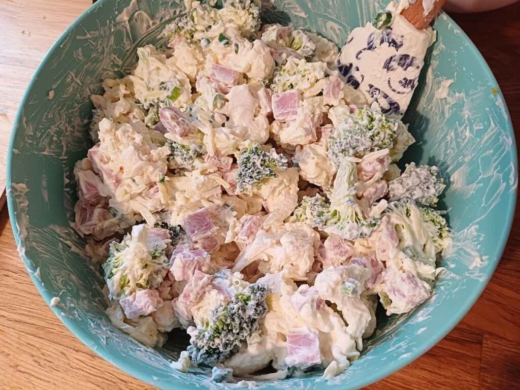 Keto ham casserole uncooked ingredients in a bowl in creamy sauce
