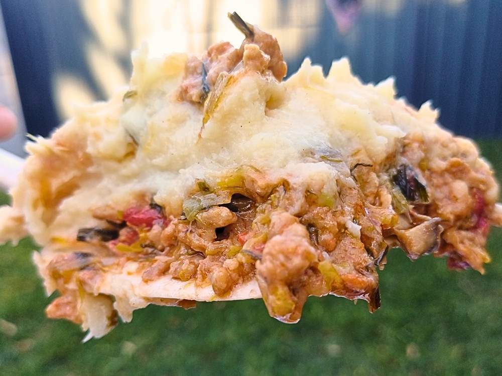 A slice of keto ground pork casserole on a serving spoon showing inside layers