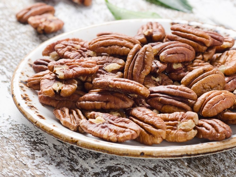 A plate of raw pecan nuts close up.