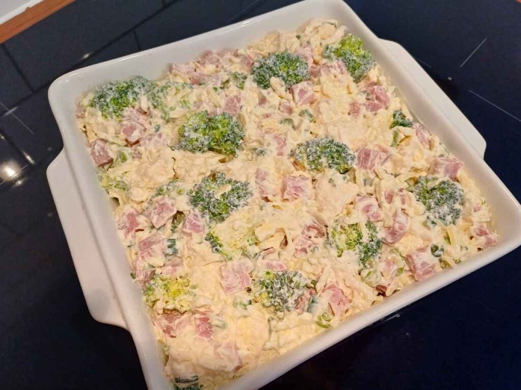 Unbaked keto ham casserole with vegetables in creamy sauce in a baking dish about to go into the oven
