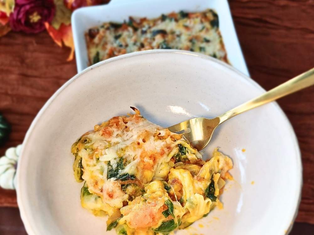 A view of a keto butternut squash casserole serving in a light colored bowl with a gold fork