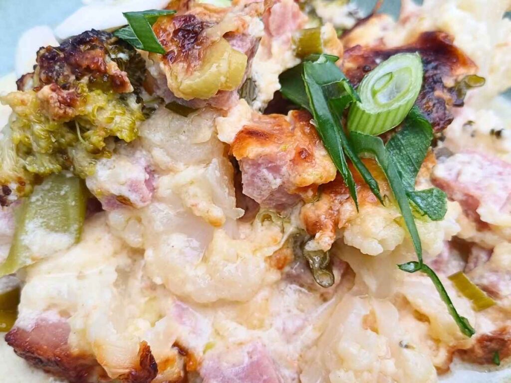Close up of a creamy casserole with ham and vegetables