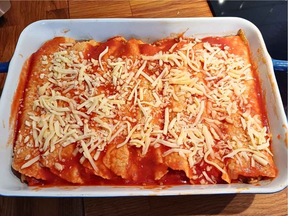 Enchiladas topped with Mexican sauce and Mexican sheed ready to go into the oven to be cooked