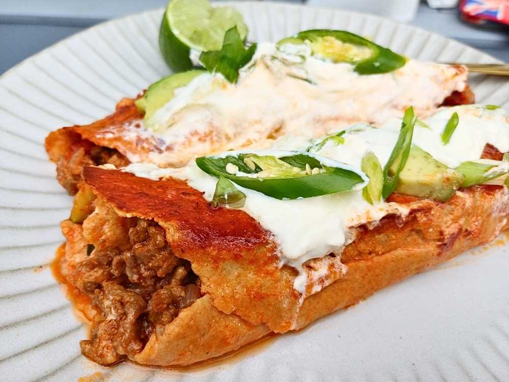 Ground beef and vegetables wrapped in a low carb tortilla and baked in the oven presented on a white plate