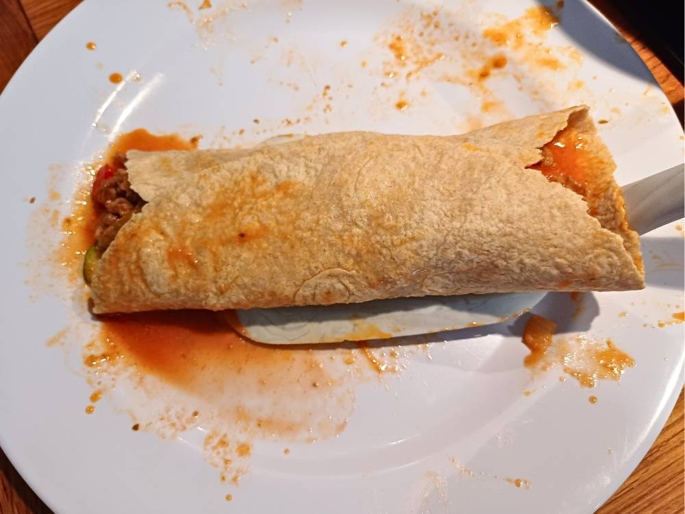 Transfering ready enchilada from a plate with a spatula