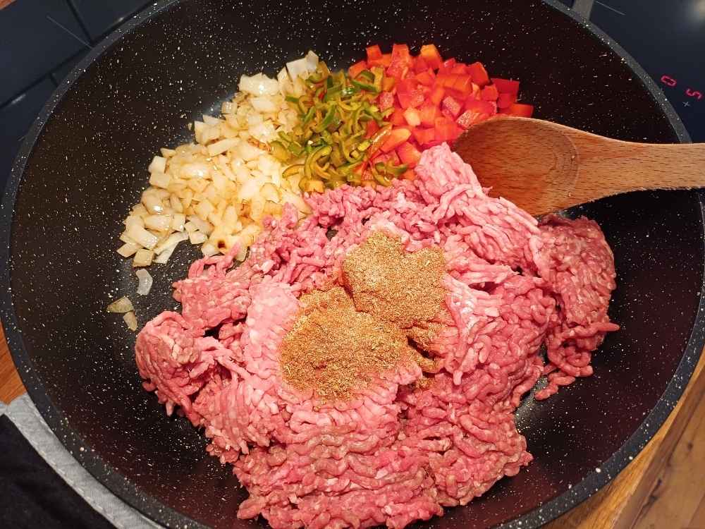 Ground beef cooking on a pan with spices and vegetables