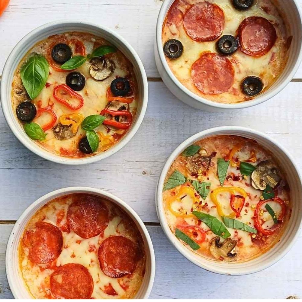 Four bowls of cottage cheese pizza bake with different toppings