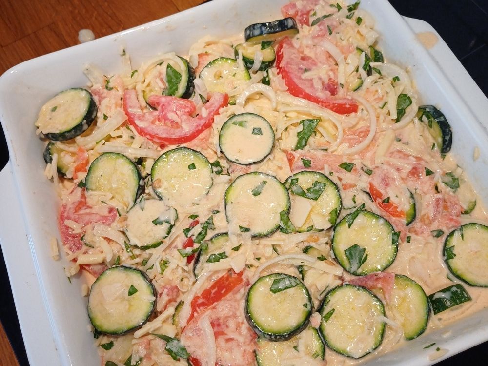 Uncooked zucchini casserole about to go into the oven in a baking dish.