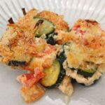 Top down view of a zucchin casserole served on a large white plate.