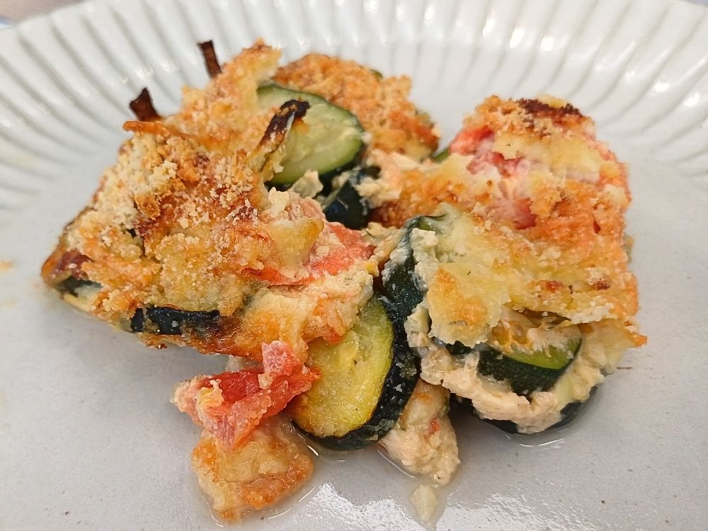 Top down view of a zucchin casserole served on a large white plate.