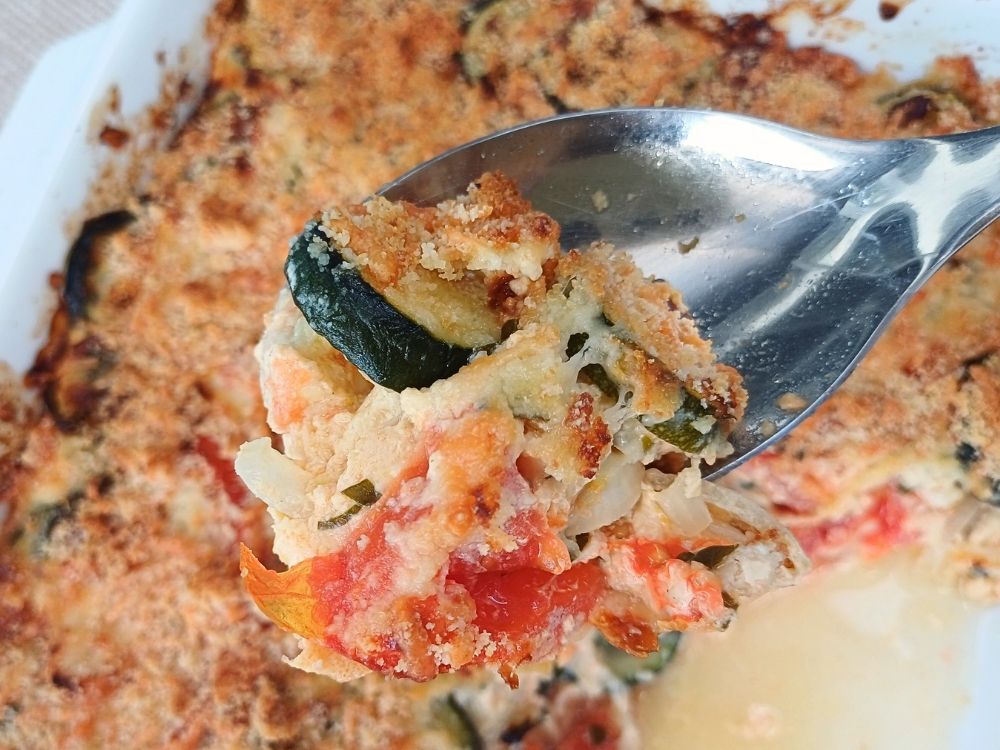 Close up of a zucchini casserole on a large serving spoon.