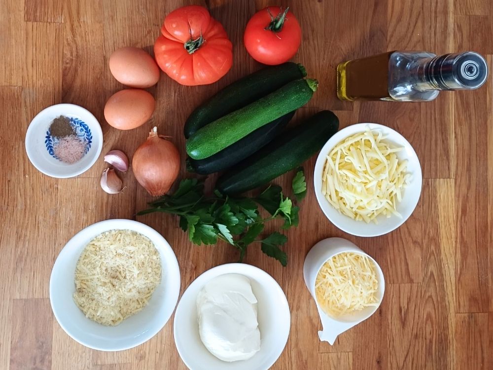 Ingredients for an Italian zucchini tomato casserole recipe laid out on a kitchen countertop