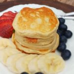 A small stack of fluffy banana cottage cheese pancakes, gluten free with berries on the side.