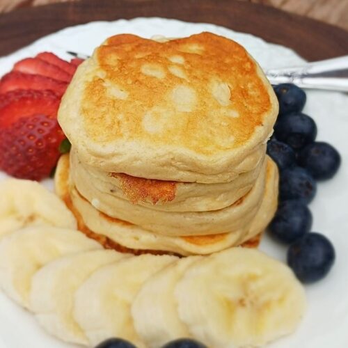 A small stack of fluffy banana cottage cheese pancakes, gluten free with berries on the side.