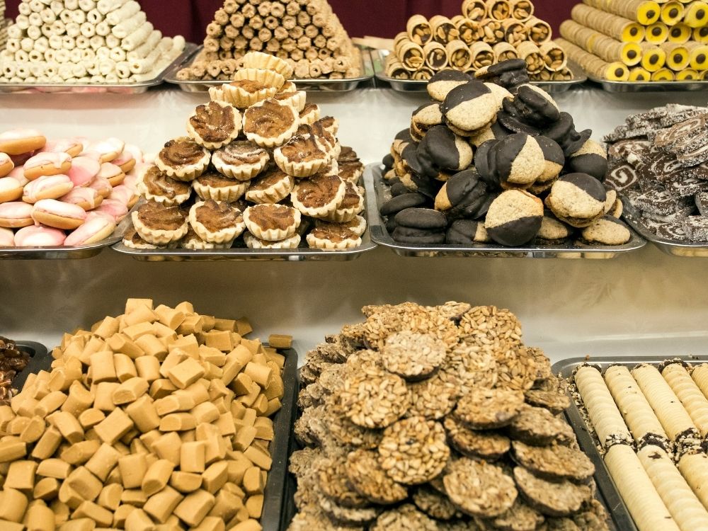 Cookie display at a dessert store piled up on trays.