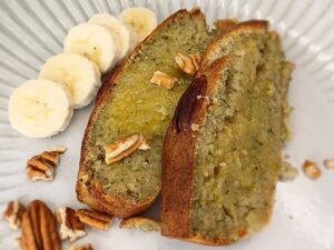 Close up of a banana zucchini bread slices with some banana by the side on a plate.