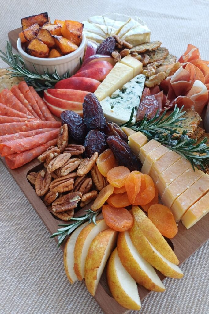 Close up of a charcuterie board with fruit, dips, cheeses and cured meats.