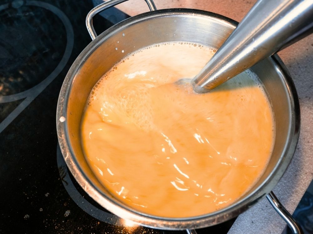 curried butternut squash soup cooking in a stainless steel pot on the stove.