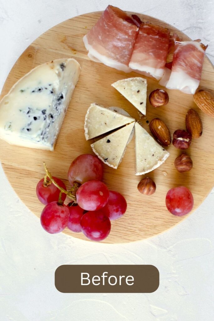 Very basic simple round cheese board with prosciutto and grapes.