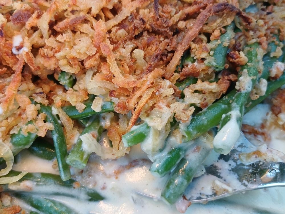 Close up image of a green bean casserole topped with crispy French onions for Thanksgiving dinner.