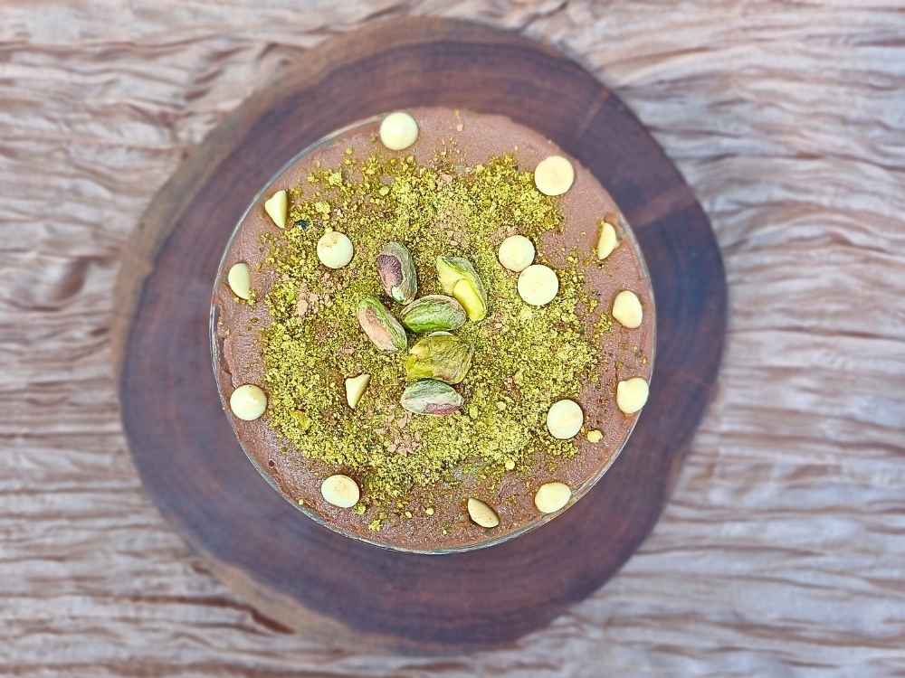 Top down view of dubai chocolate chottage cheese mouse showing topping like crushed pistachios and white chocolate chips.