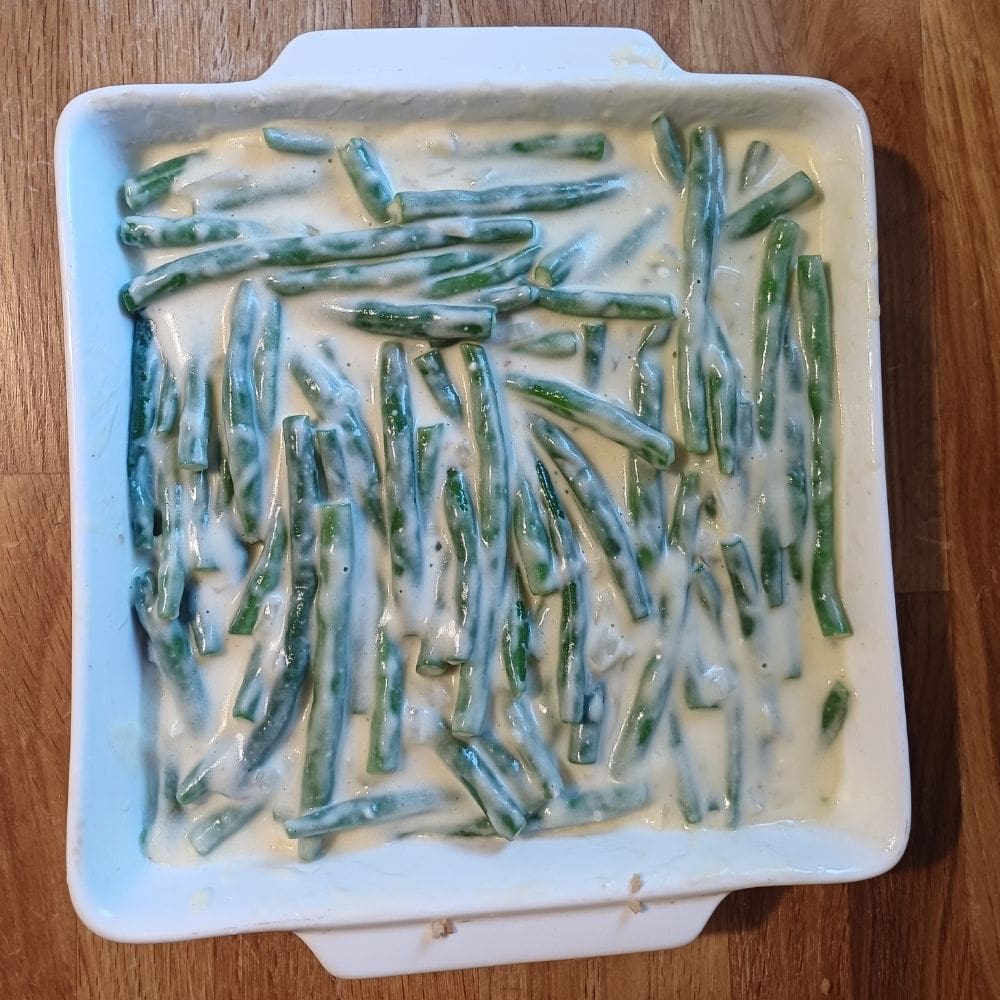 Green beans in creamy sauce in a white square baking dish