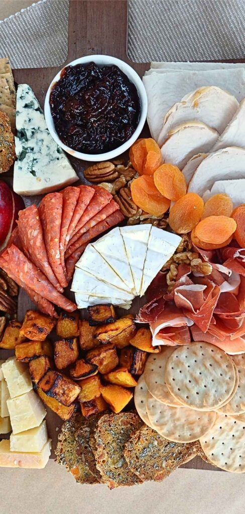 Top down view of a Thanksgiving charcuterie board with cured meats, cheeses, turkey and roasted pumpkin cubes
