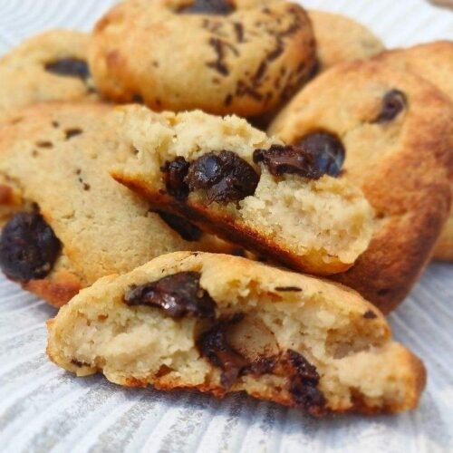 Chocolate chip cottage cheese cookies broken in pieces to show the inside of the soft chewy cookie on a leaf decorative plate