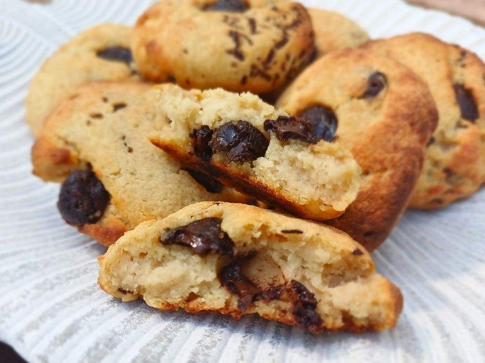 Chocolate chip cottage cheese cookies broken in pieces to show the inside of the soft chewy cookie on a leaf decorative plate