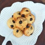 Top down view of a batch of chocolate chip small cookies on a white leaf shaped plate