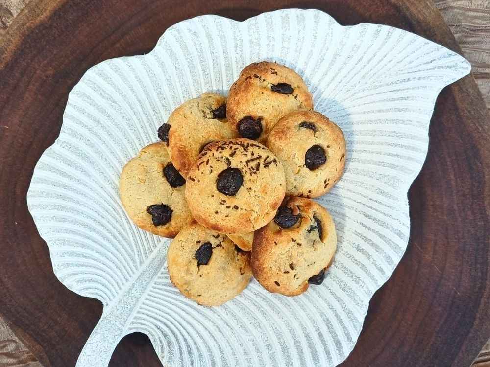 Top down view of a batch of chocolate chip small cookies on a white leaf shaped plate